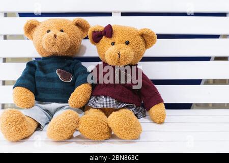 Teddybären sitzen zusammen auf dem weißen Holzstuhl. Valentinstag. Wort Liebe Herz. Paar Teddybären, Umarmung, Umarmung, Datum. Retro-Vintage Stockfoto