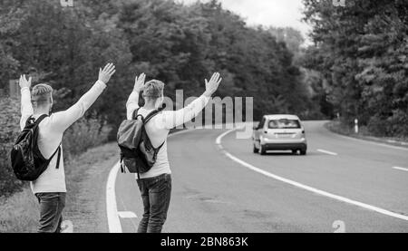 Nur Freunde und Straße voran. das Gefühl der Freiheit. Mit Freunden unterwegs. Anreise per Autostop. Hoffnungslos hitchhiker. Männer versuchen stop Auto. Zwillinge zu Fuß entlang der Straße. Wanderer Mann auf der Straße. Art des Reisens. Stockfoto