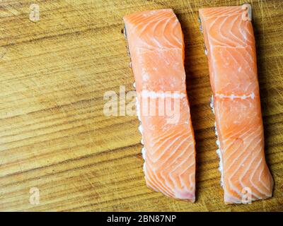 Zwei rohe Lachsfilets auf einem Holzhackbrett mit Kopierfläche Stockfoto