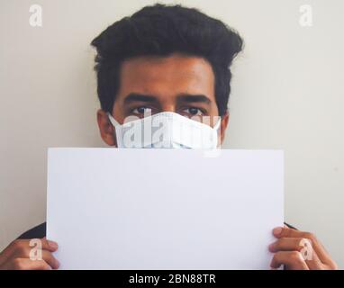 Ein Mann trägt Gesichtsmaske mit weißem Brett, Konzept des Aufenthalts zu Hause. Stockfoto