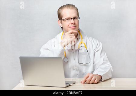 Doctor Mann sitzt an einem Tisch mit einem Laptop. Nahaufnahme. Stockfoto