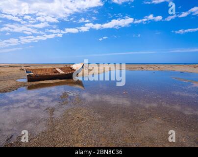 Wilde sardische Küstenlandschaft mit einem alten, blauen Holzboot am goldenen Strand Stockfoto
