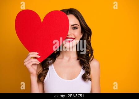 Foto von ziemlich fröhlich Dame halten große Papier Herz Postkarte versteckt halb Gesichtsausdruck 14 februar Romantik Datum präsent tragen weiß casual Singlet Stockfoto