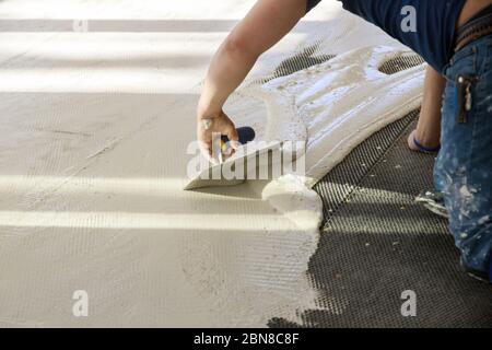 Professionelle Arbeiter Zerklurmbeton in Vorbereitung für die Verlegung für Fliesenleger auf dem Boden. Stockfoto