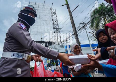 Makassar, Indonesien. Mai 2020. Die Verkehrspolizei Süd Sulawesi verteilt Lebensmittel, um schnell zu brechen, und maskiert Fußgänger und Autofahrer auf den Straßen. (Foto: Herwin Bahar/Pacific Press/Sipa USA) Quelle: SIPA USA/Alamy Live News Stockfoto