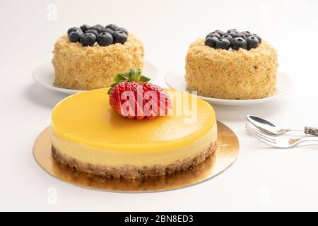 Mango-Kuchen mit Erdbeeren und Muffins mit Heidelbeeren überbacken. Hausgemachtes Backen. Auf einem goldenen Karton weiße Platten. Diät Süßigkeiten Stockfoto