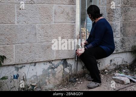 Jerusalem, Israel. Mai 2020. Familien verbringen Zeit mit älteren Menschen in einem betreuten Wohnheim unter strengen sozialen Distancing Beschränkungen, die Besucher verbieten, durch einen Bereich in einer Hintergasse zu diesem Zweck eingerichtet. Gemäß der Richtlinie ‘no kissing, no Umarming, no touching' des Gesundheitsministeriums wird durch diese Regelung sichergestellt, dass zwei Meter Abstand beibehalten oder durch eine transparente Trennwand interagiert werden können. Quelle: Nir Alon/Alamy Live News Stockfoto