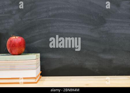 Roter Apfel auf dem Buch mit schwarzen Brett als Hintergrund ruhend, zurück zur Schule Konzept. Stockfoto