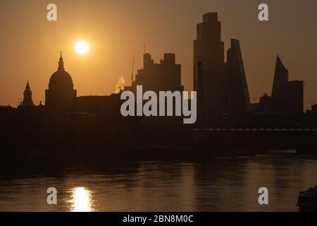 Sunrise in London schafft eine Silhouette der City of London und der St. Paul's Cathedral mit der Themse im Vordergrund. Stockfoto
