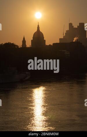 Sunrise in London erzeugt ein Silhouette-Profil der Kuppel der St. Paul's Cathedral mit der Themse im Vordergrund Stockfoto