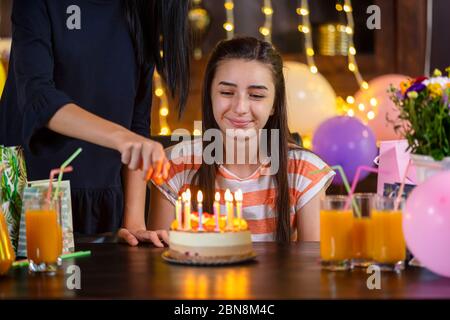 Happy teen Mädchen und Mutter mit Geburtstagskuchen bei Jubiläums-Party. Kerzen auf Geburtstagskuchen anzünden. Stockfoto