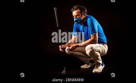 Golfer mit Maske für COVID-19 studiert das Grün vor dem Schuss, isoliert auf schwarzem Hintergrund Stockfoto