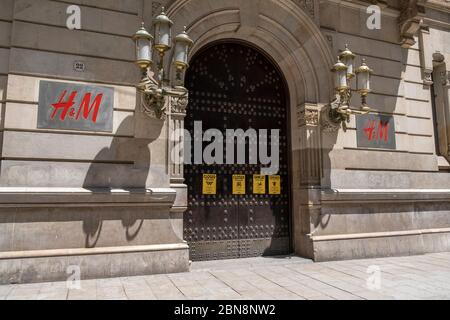 Barcelona, Spanien. Mai 2020. Kritische Plakate gegen das zerstörerische und extraktivistische kapitalistische System werden an der Tür des schwedischen Stores H&M (Hennes & Mauritz) von der Umweltgruppe Rebellion oder Extinction Barcelona während der Covid-19-Pandemie ausgestellt. Quelle: SOPA Images Limited/Alamy Live News Stockfoto