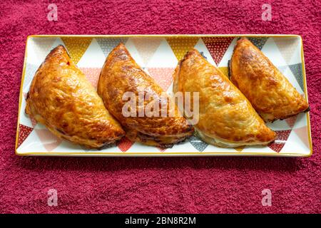 Vier hübsch gebräunte hausgemachte Backwaren (Apfel- und Birnenrisoles) Stockfoto