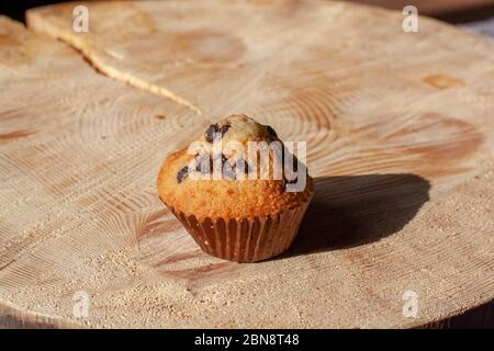 Muffin mit Rosinen auf einem Holzständer in der Sonne. Hausgemachtes Backen. Selektiver Fokus auf den Cupcake. Horizontal. Stockfoto