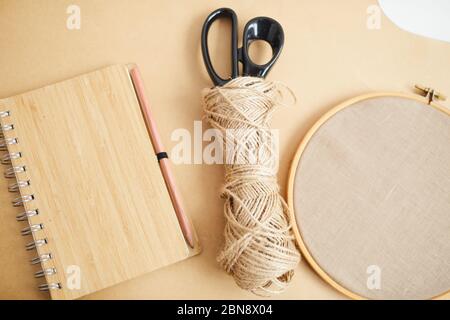 Nahaufnahme der Schere und des Fadens der Notizblock, die auf dem Holztisch liegen und die Handarbeiten vorbereiten Stockfoto