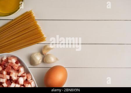 Kochzutaten für italienische Carbonara auf rustikaler Oberfläche. Pasta, Spaghetti mit Pancetta, Ei, Parmesan, Speck, Sahne, Knoblauch, Olivenöl. Draufsicht, Stockfoto