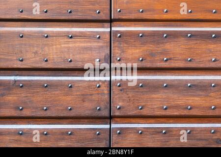 Textur von grobkörmigen Holzwand oder Tür von italienischen alten mittelalterlichen Gebäude. Bemalte Tür Textur einer mittelalterlichen Burg. Braune Holzdielen mit Metall Stockfoto