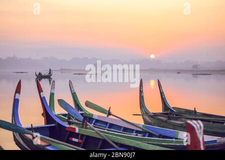 Bunte Boote am Ufer mit Sonnenaufgang in der Nähe der U Bein Brücke, Taungthaman See in der Nähe von Amarapura, Myanmar Stockfoto