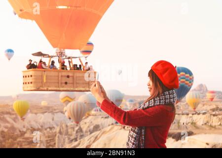 Asain Frau genießen Sie die Aufnahme von Heißluftballons fliegen über erstaunliche Felslandschaft in Kappadokien. Stockfoto