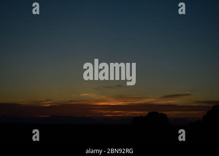 Wunderschöner Sonnenuntergang Blick auf die leuchtenden Wolken über den Bäumen Stockfoto