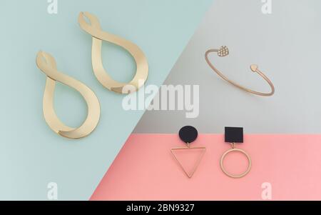 Abstraktes Layout von modernen Design-Schmuck. Goldene Ohrringe und Armband auf Pastellfarben Papier Stockfoto