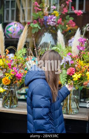Junge lächelnde Frau Auswahl frische Blumen in der Vorderseite des Blumenladen aussetzen Stockfoto