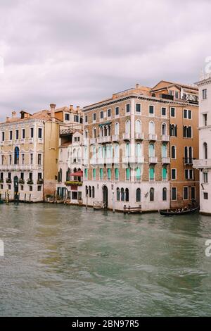 Eine Gondel mit Touristen segelt entlang des Canale Grande inmitten der Fassaden venezianischer Häuser, die in Venedig, Italien, auf dem Wasser stehen. Stockfoto