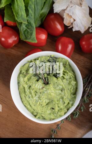 Glutenfreie, frisch gekochte Penne-Pasta aus grünen Erbsen auf Holzbrett isoliert. basilikum, Tomaten, Avocado und Koriander in einer weißen Schüssel. Schuss von oben Stockfoto