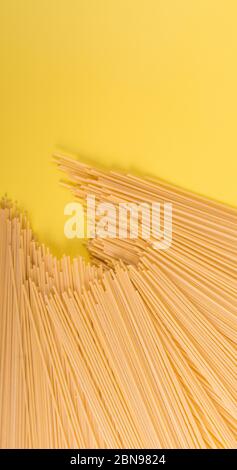 Ungekochte gelbe lange Spaghetti auf rustikalem Hintergrund. Gelbe italienische Pasta. Lange Spaghetti. Rohe Spaghetti Bolognese. Hintergrundkonzept für Lebensmittel. Einfach Stockfoto