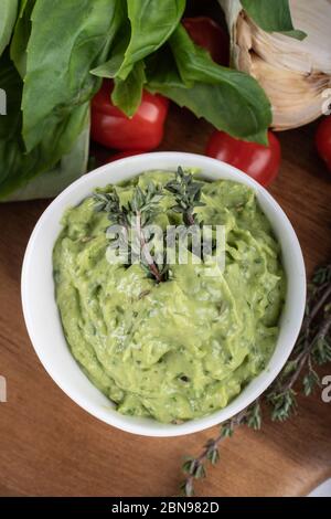 Glutenfreie, frisch gekochte Penne-Pasta aus grünen Erbsen auf Holzbrett isoliert. basilikum, Tomaten, Avocado und Koriander in einer weißen Schüssel. Schuss von oben Stockfoto