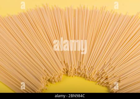 Ungekochte gelbe lange Spaghetti auf rustikalem Hintergrund. Gelbe italienische Pasta. Lange Spaghetti. Rohe Spaghetti Bolognese. Hintergrundkonzept für Lebensmittel. Einfach Stockfoto