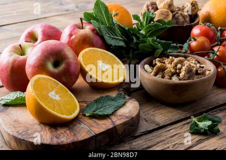 Farbenfroher Sommersalat mit Spinat, Orange, Kirschtomaten, Walnuss, Feigen, Quinoa, frischem Fruchtklementine Zitrusfrüchten im Hintergrund, auf holzbüschel Stockfoto