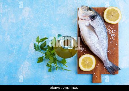 Frisch gefangener und gereinigter Brassen, fertig zum Kochen mit Tomaten, Knoblauch, Öl und Petersilie Stockfoto