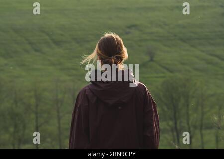 Hinter einer Frau, die bei windigem Wetter auf den Hügeln steht. Wandern, Wandern und verbringen Freizeit im Freien, junge Erwachsene Portait Stockfoto