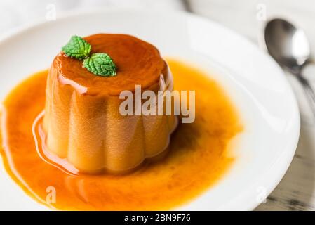 Nahaufnahme einer Flan Creme Karamellpudding mit Minze, ein Pudding Dessert. Stockfoto