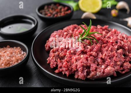 Frisches Hackfleisch Hackfleisch Hackfleisch auf einem schwarzen Teller vor Steinhintergrund. Stockfoto
