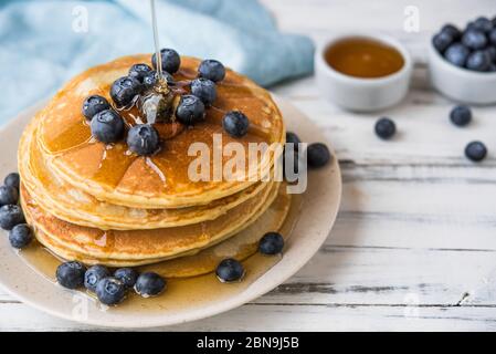 Nahaufnahme eines Stapels flauschiger Pfannkuchen mit Ahornsirup über sie gegossen. Stockfoto