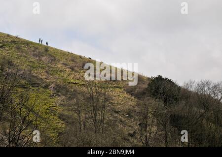 Drei Personen und ein Hund auf einem Teufelskerl-Spaziergang auf einem Grat auf South Downs, West Sussex, England. Stockfoto