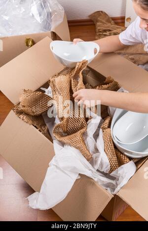 Detail der Frau Verpackung zerbrechlichen Artikel mit zerknittert Verpackungspapier. Konzept des ein- und Ausfahrens. Stockfoto