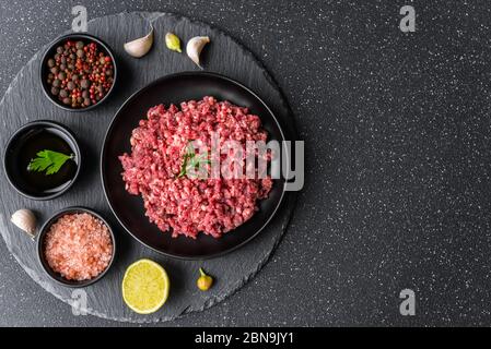 Frisches Hackfleisch Hackfleisch Hackfleisch auf einem schwarzen Teller vor Steinhintergrund. Stockfoto