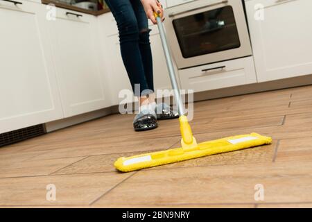 Eine Frau wäscht in ihrem Haus Fußbodenheizung. Ein Mopp in den Händen einer Haushälterin. Stockfoto