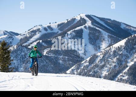 Eine Frau, die an einem schönen Wintertag im Sun Valley mit ihrem fetten Fahrrad unterwegs ist. Stockfoto