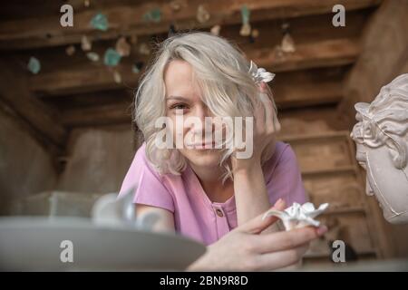 Ein blondes Mädchen in einem beige gelb karierten Anzug mit einem Rock in High Heels mit ihren Haaren in einem Pferdeschwanz posiert im Stidio Stockfoto