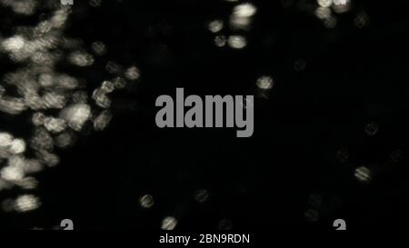 Bokeh Sonnenblendung reflektiert in Wasseroberfläche. Sonnenstrahlen flackern in der Wasseroberfläche. Schimmerndes Wasser in der Sonne. Abstrakt verschwommen aus dem Fokus Bokeh backgroun Stockfoto