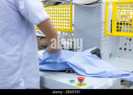 Automatische Bügelmaschinen für Strickwaren und Hemden mit Presse in der Textilfabrik. Stockfoto