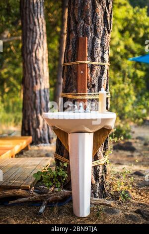 Ein funktionierendes Waschbecken, das in einem Glamping an einen Baum geschnallt ist Lager Stockfoto