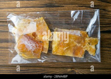 Getrocknetes Kabeljaufilet in einer transparenten Verpackung Vorspeise zu Bier auf Holzhintergrund. Snack Fisch zu Bier. Nahaufnahme Stockfoto