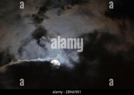 Schöner Nachthimmel mit dem Mond, der teilweise von Wolken verdeckt ist Stockfoto