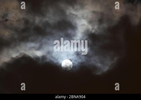 Schöner Nachthimmel mit dem Mond, der teilweise von Wolken verdeckt ist Stockfoto